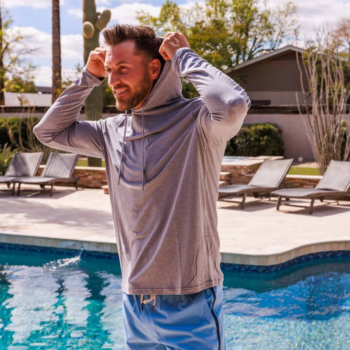 man by the pool covering his head with a hoodie