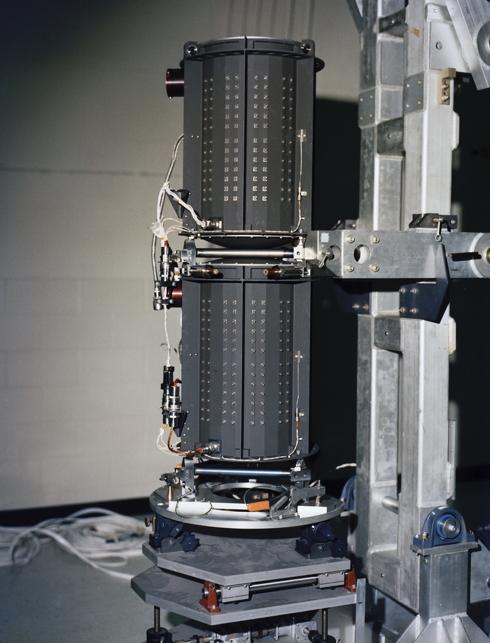 Two cylindrical metal machines stacked on top of each other in a cinder block room