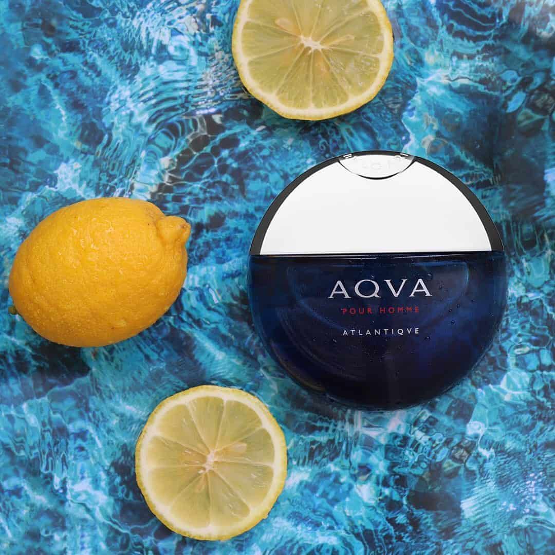 a bottle of aqva pour homme atlantiqve and lemons floating on the water