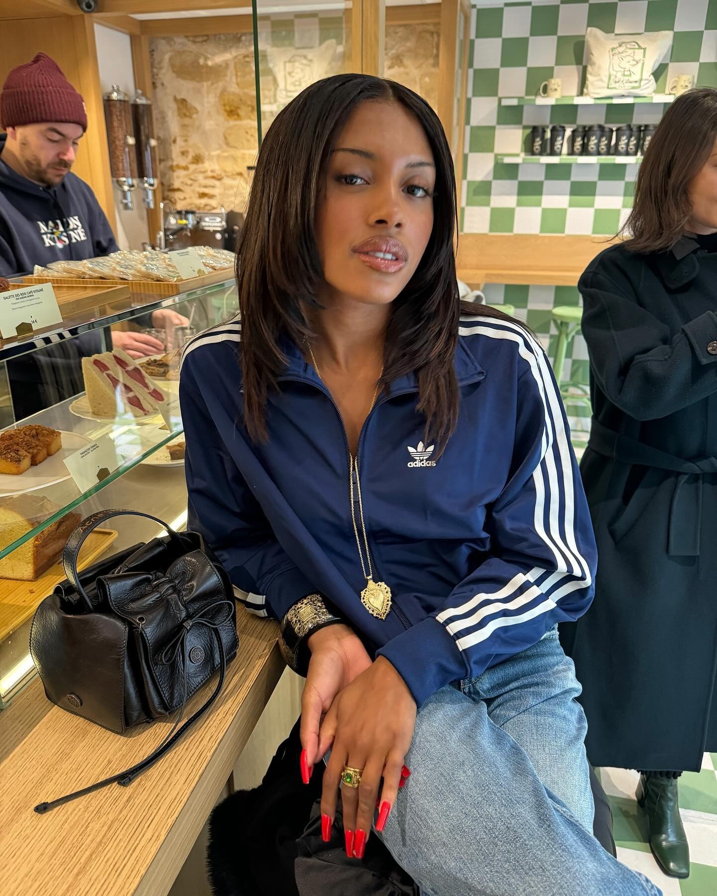 A woman sitting in a cafe in a blue Adidas top with face-framing layers